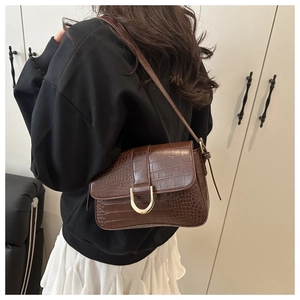 Detailansicht der braunen Kroko-Schultertasche mit goldener U-förmiger Metallschnalle