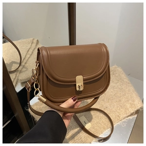 Close-up of retro dark brown saddle bag with golden metal twist lock and leather texture