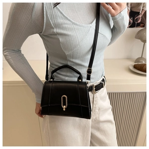 Gros plan d'un sac à main noir en cuir avec verrou doré et poignée élégante