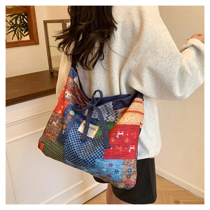 Detailed view of colorful patchwork denim tote bag with drawstring bow and floral patterns