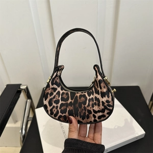 Mini borsa a mezzaluna con stampa leopardata e cerniera dorata tenuta su sfondo neutro