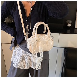 Detail of cream white mini crossbody bag with 3D floral embossing and a lace bow charm