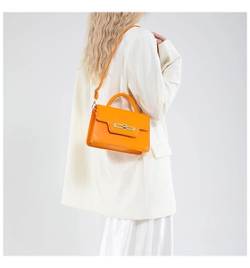 Orange polished leather small square bag with gold metal lock on white blazer model