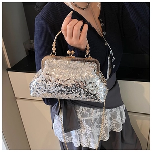 Close-up of sparkling silver sequin evening clutch with floral engraved gold handle