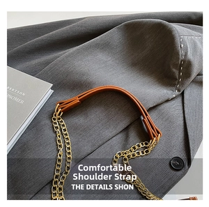 Détail d'une bandoulière en cuir marron avec chaînes en métal doré pour un sac cabas