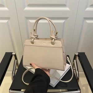 Minimalist beige leather tote bag with FASHION TREND logo and gold hardware on white book