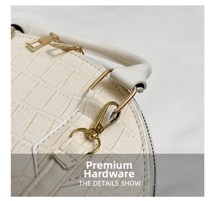 Close-up of golden metal hardware and crocodile texture on beige shell handbag