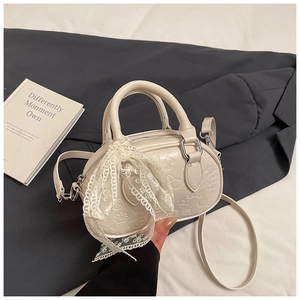 Detail of a creamy white mini handbag with embossed floral patterns and lace bow