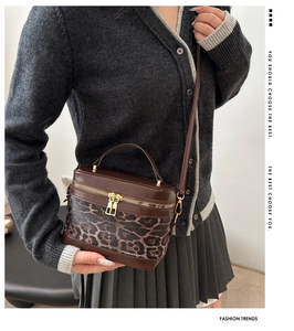 Detail view of leopard print box bag with gold double zippers and brown faux leather trim