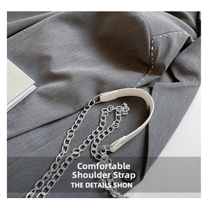 Detail of white leather shoulder strap and polished silver metal chain on casual blazer