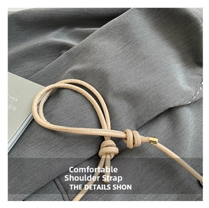 Detail of beige leather bag strap with knotted design and gold metal end caps