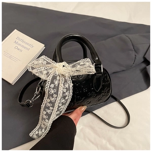 Detail of black embossed handbag with a large white lace bow charm and cartoon patterns