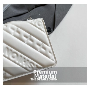 Macro detail of white quilted faux leather bag with star pattern and silver chain