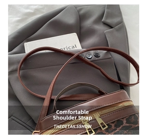 Macro detail of leopard print bucket bag featuring brown leather trim and dual zippers