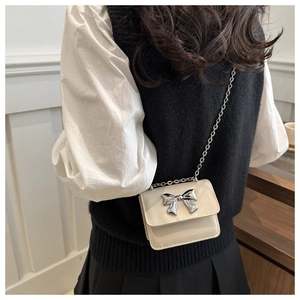 Mini cream PU leather crossbody bag with silver bow buckle worn on chain strap