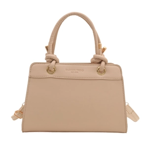 Minimalist beige tote bag with knotted handles and gold hardware in a sleek trapezoid shape