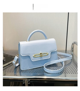 Detail view of the elegant light blue crossbody bag featuring a golden chain link buckle