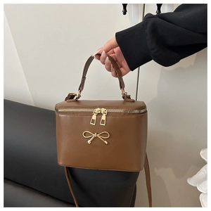 Detail of brown box bag with gold metal bow clasp and high-quality leather texture