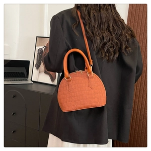 Detail of orange crocodile embossed shell bag with gold zippers and sleek handle
