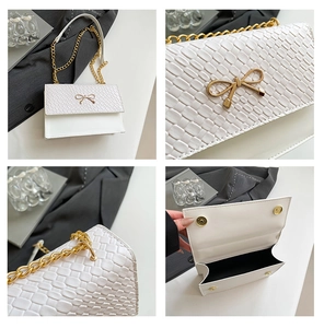 Detail of white crocodile texture bag featuring gold bow hardware and metal chain strap