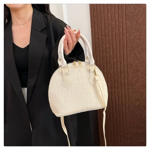 Detail of cream shell bag with crocodile texture, golden hardware and shoulder strap