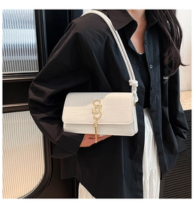 Close-up of white crocodile pattern shoulder bag with gold letter buckle and tassel