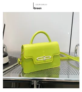 Detail of neon green glossy leather square handbag with silver metal lock on wire rack