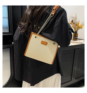 Détail de la texture tissée et de la bordure en cuir caramel d'un sac à bandoulière