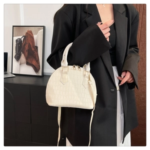 Detail of white crocodile pattern shell bag with gold hardware and cylindrical handles