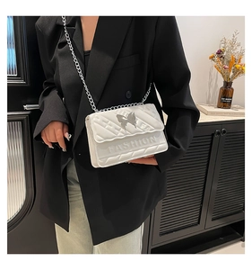 Quilted white leather crossbody bag with silver butterfly charm and chain strap details