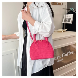 Hot pink crocodile pattern shell bag held by model wearing a minimalist white shirt
