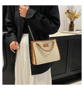 Détail du sac en toile beige avec bordures en cuir marron et chaîne dorée