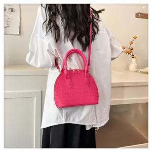 Detail of rose pink shell bag with crocodile pattern texture and golden hardware