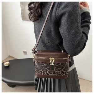 Detail of crossbody leopard print box bag with golden zippers and leather handle