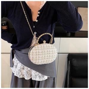 Detailed close-up of white tweed shell bag with gold metal frame and chain strap