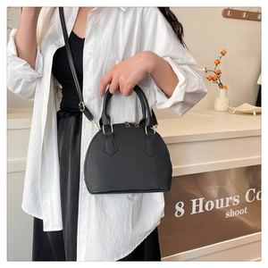 Detail of black crocodile texture shell bag with golden double zipper and round handle