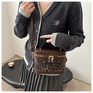Detail of leopard print bucket bag featuring brown leather trim and gold zippers