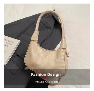 Detail of beige woven hobo bag with gold chain accent and textured crescent design