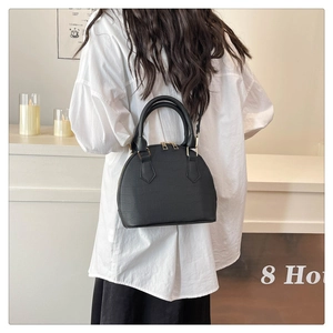 Detail of elegant black crocodile pattern shell bag with golden zipper and sturdy handles