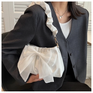 Detail of white satin bow bag featuring a ruffled handle and elegant gold-tone hardware