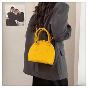 Detailed view of crocodile texture on bright yellow minimalist shell handbag