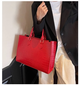 Detailed view of the red crocodile pattern leather texture on a large tote handbag