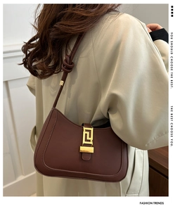 Dettaglio borsa baguette in pelle marrone scuro con fibbia dorata e nodo sulla tracolla