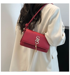 Detail of red crocodile texture crossbody bag with gold S-logo and fringe tassel