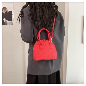 Detail of red crocodile pattern shell bag worn over the shoulder on a grey blazer