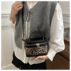 Detail of a chic leopard print and black leather box bag with gold-tone dual zippers