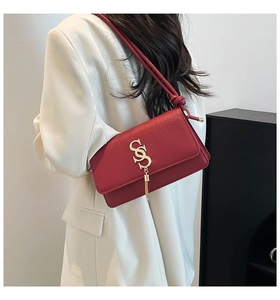 Detailed view of red crocodile embossed leather shoulder bag with gold SS logo and tassel
