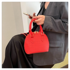 Detail of red croc-embossed shell bag featuring golden zippers and a chic handle