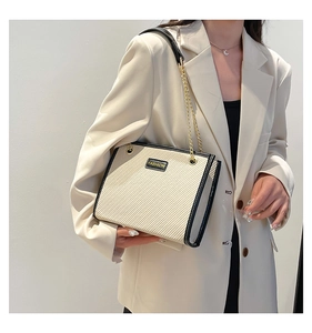 Détail du sac cabas en toile crème avec bordures en cuir contrastées et chaîne dorée