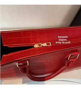Detail of red crocodile texture tote bag featuring smooth gold metal zipper and handle rings